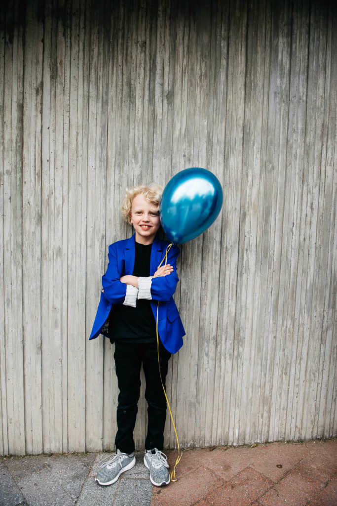 Child with a pink balloon, surrounded by illustrated raindrop lights on a textured wall.