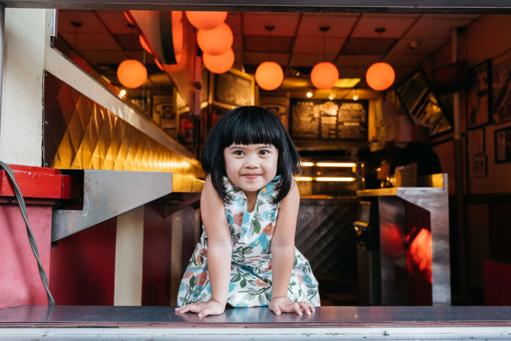 Young boy holding a camera, taking a picture near an amusement park.