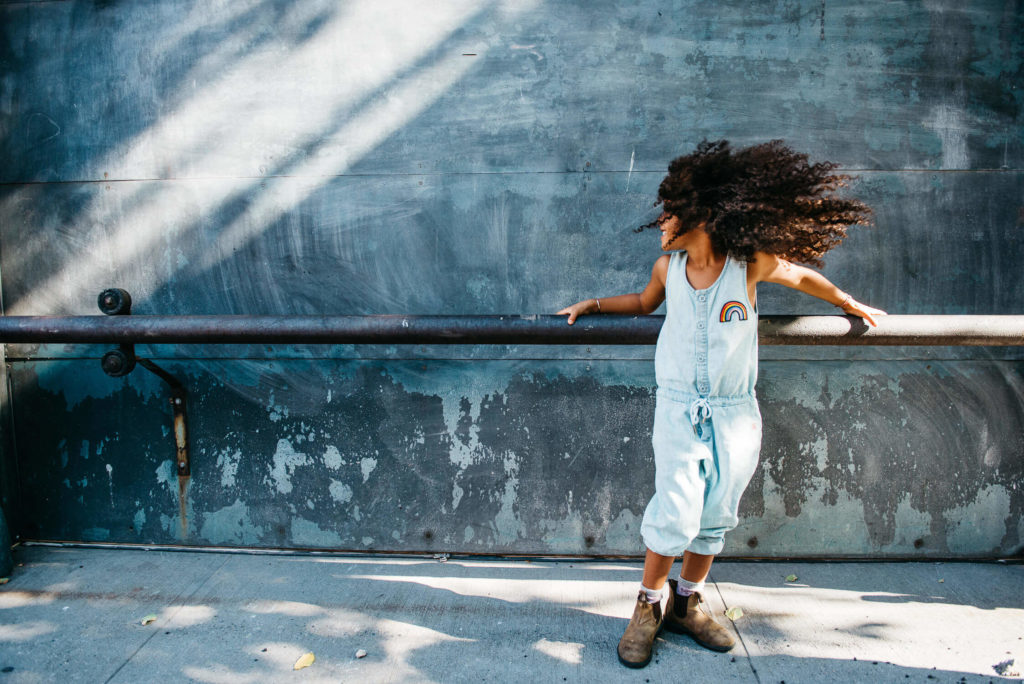 Girl in a pink sweater smiling with wind blowing through her hair by a lake.