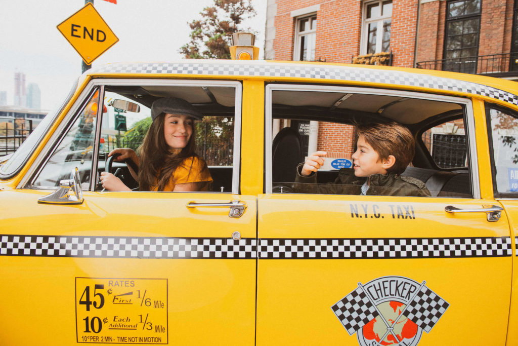 young boy and woman sitting in a classic yellow taxi, showcasing a New York city vibe