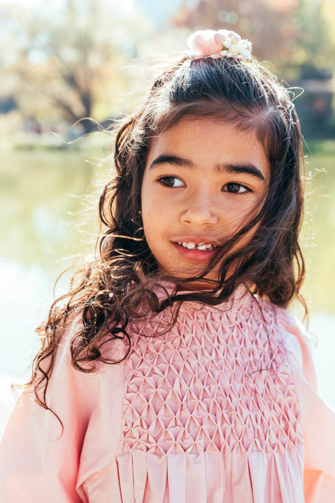 Little girl in a dress smiling and leaning out of a food truck window.