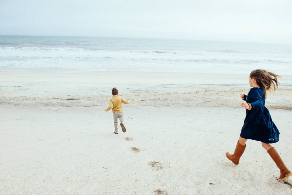 children running along the beach, leaving footprints in the sand behind them