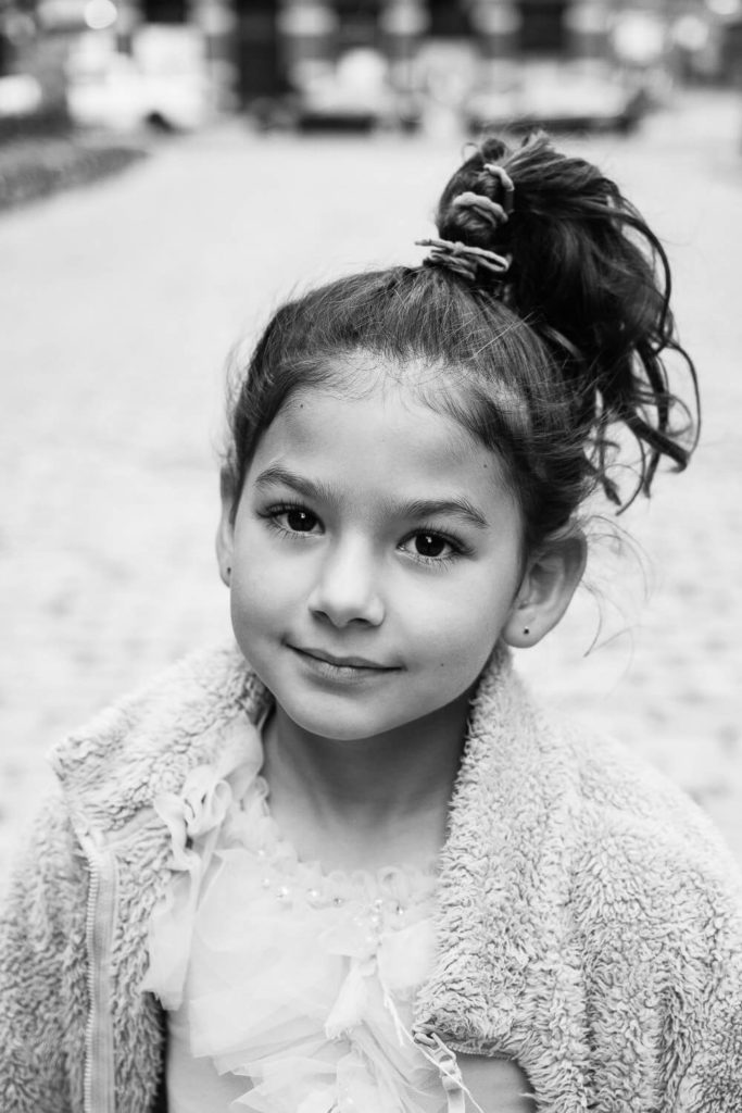close-up portrait of a young girl with a soft smile, wearing a cozy sweater, black and white