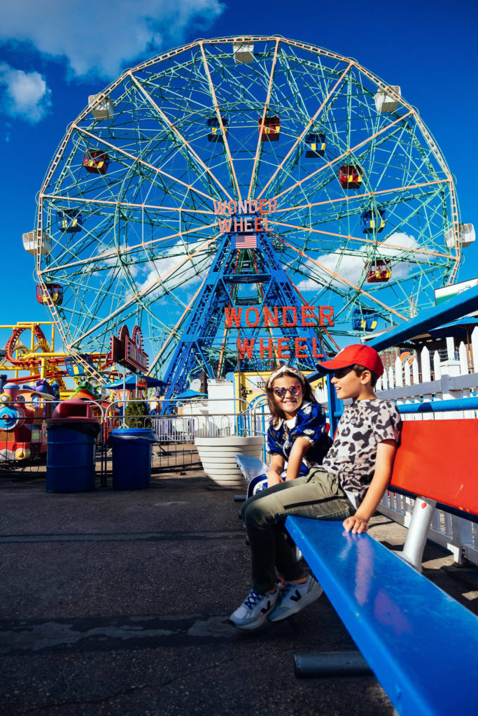 Kids sitting on a bench at Coney Island with Wonder Wheel in the background