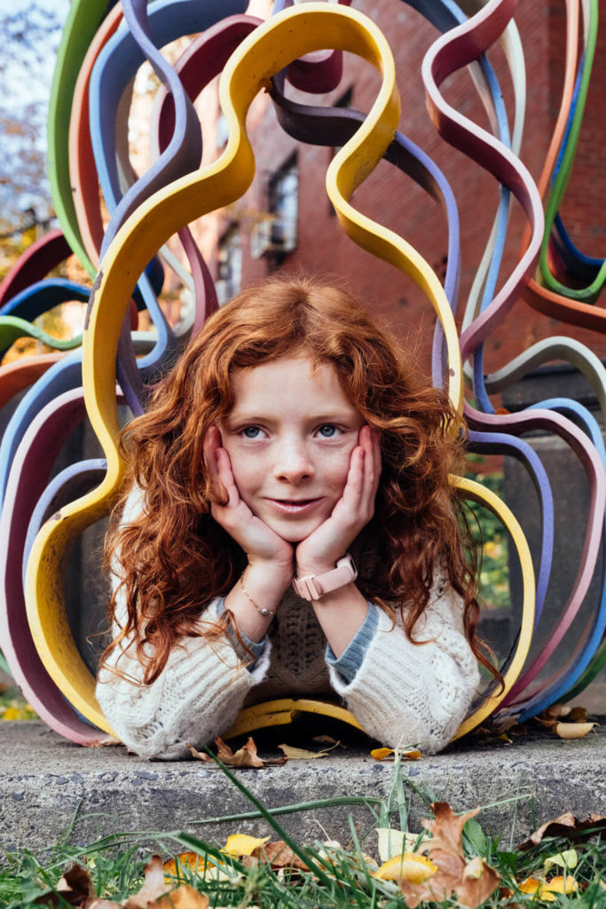 girl laughing in front of colorful heart mural, vibrant kids portrait session