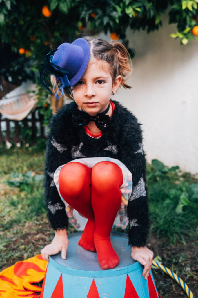 Quirky girl in red tights and a blue hat, showcasing her unique style during a kids’ portrait session.