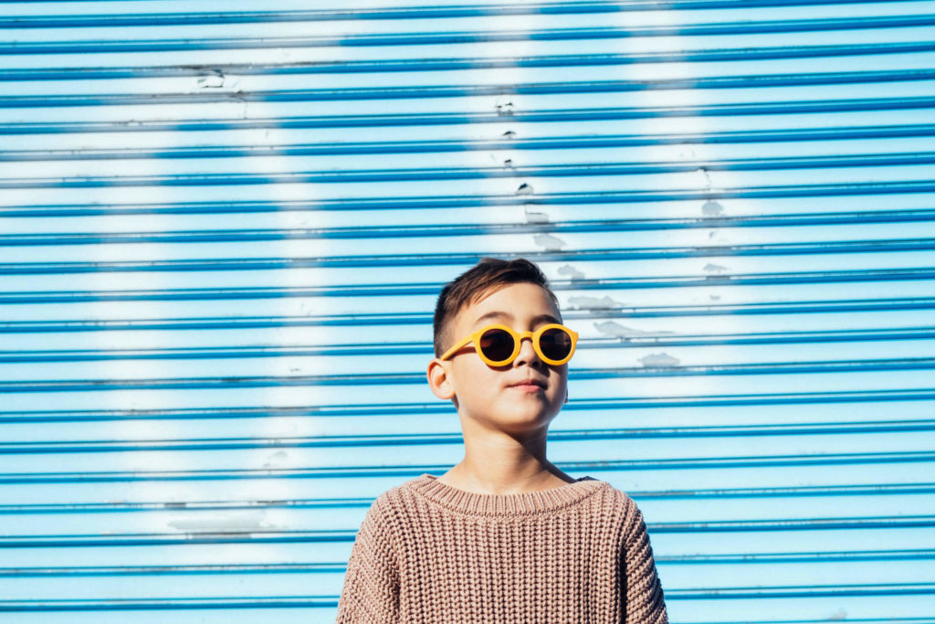Three children joyfully jumping in front of a colorful graffiti mural.