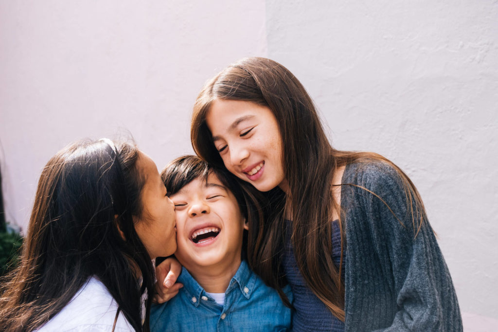 two sisters sharing a sweet moment, kissing and laughing together